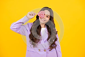 Teen girl hold lollipop caramel on yellow background, candy shop. Teenager with sweets suckers. Happy teenager, positive