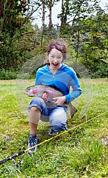 Girl holding large rainbow trout with huge smile