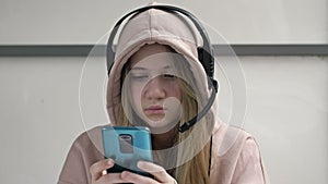 Teen girl holding phone obsessed with smartphone social media apps sitting alone at home. Technology addicted teenager