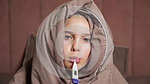 Teen girl holds thermometer in mouth measuring temperature