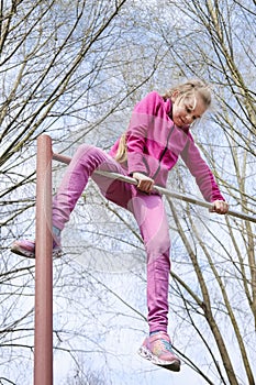 Teen girl on the horizontal bar in the park. Outdoors activity