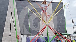 a teen girl jumps on a bungee trampoline. entertainment for children in park.