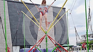 a teen girl jumps on a bungee trampoline. entertainment for children in park.