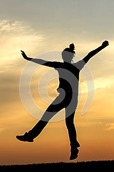 Teen girl jumps for joy at sunset.