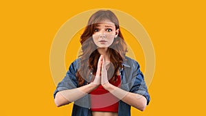 Teen Girl Keeping Hands In Praying Gesture On Yellow Background