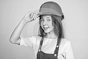 teen girl laborer in protective helmet and uniform on grey background, welcome