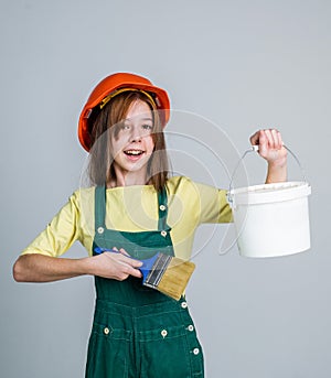 teen girl laborer in protective helmet and uniform use painting brush and bucket, labor day