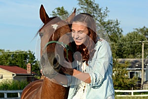 A teen girl laughs with her horse