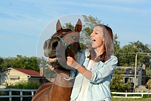 A teen girl laughs with her horse