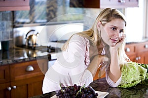 Teen girl leaning on kitchen counter daydreaming
