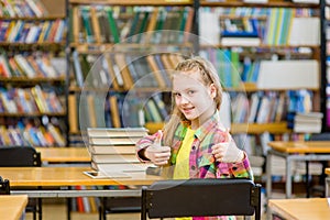 Teen girl in library showing thumbs up