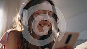 Teen girl listening music in headphones closeup. Happy female typing message