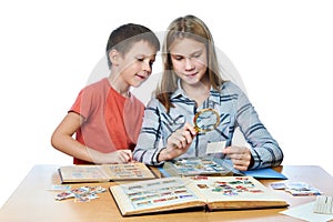 Teen girl and little boy with magnifier looking his stamp collection isolated