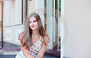 Teen girl with long brunette hair sitting on the marble steps