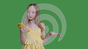 Teen girl with long hairs is browsing her mobile phone on keyed green background.