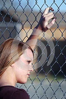 Teen girl looking through fence