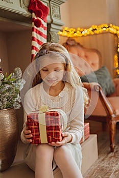 Teen girl looking on present near Christmas tree