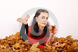 Teen girl lying on autumn leaves with drink