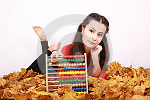 Teen girl lying on dried leaves with abacus