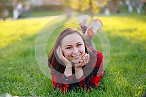 Teen girl lying on the grass on a Sunny day and smiling, girl with developed body smiling in the Park on the lawn