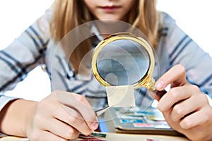 Teen girl with magnifier looks his stamp collection