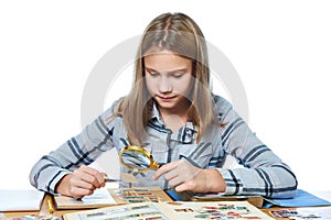 Teen girl with magnifier looks his stamp collection isolated