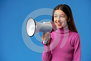 Teen girl making announcement with megaphone on blue background