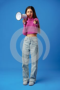 Teen girl making announcement with megaphone on blue background