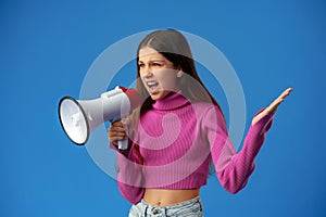 Teen girl making announcement with megaphone on blue background