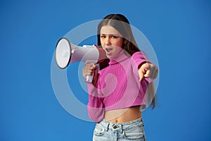 Teen girl making announcement with megaphone on blue background