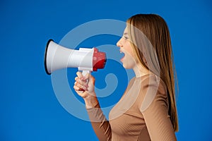 Teen girl making announcement with megaphone on blue background