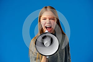 Teen girl making announcement with megaphone on blue background