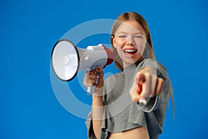 Teen girl making announcement with megaphone on blue background