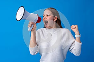 Teen girl making announcement with megaphone at blue studio