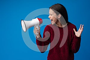 Teen girl making announcement with megaphone at blue studio
