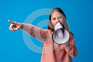 Teen girl making announcement with megaphone at blue studio