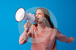Teen girl making announcement with megaphone at blue studio