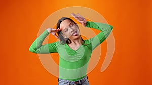 Teen girl making funny faces against orange background in studio