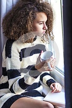 Teen girl with mug by window