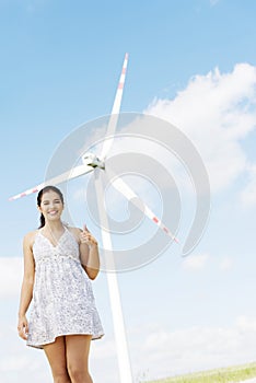 Teen girl next to wind turbine.