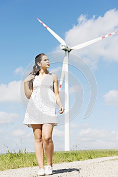 Teen girl next to wind turbine.