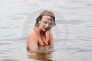 Teen girl in orange dress dabbles in water