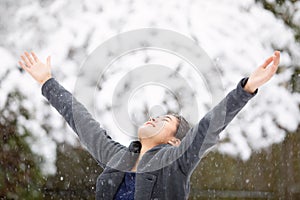Teen girl outdoors arms outstretched enjoying snowfall in winter