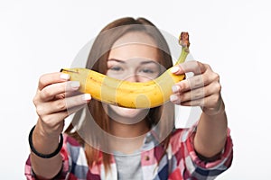 Teen girl outstretching giving you a banana, forming a creative smile in front of her face