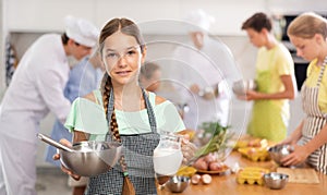 Teen girl participating in culinary workshop led by professional chefs for tweens photo