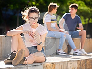 Teen girl with phone on summer city street