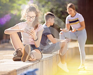 Teen girl with phone on summer city street