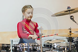 Teen girl playing the drums. Teen girls are having fun playing drum sets in music class. Girl in red drumming