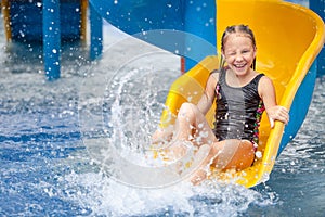 Teen girl playing in the swimming pool on slide