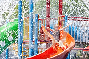 Teen girl playing in the swimming pool on slide